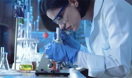 Female scientist looking down a microscope